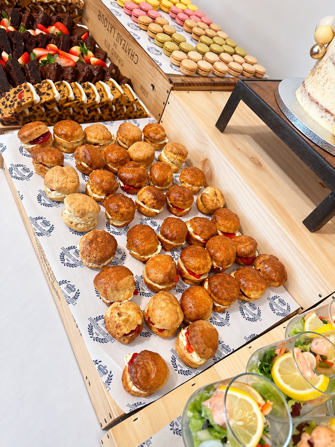 Scones with cream and jam alongside macarons, cakes and salad cups
